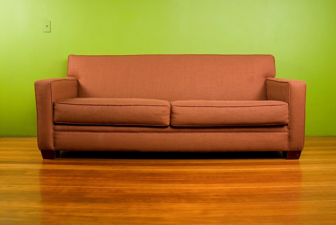 Brown 2 seater sofa on a shiny wooden floor